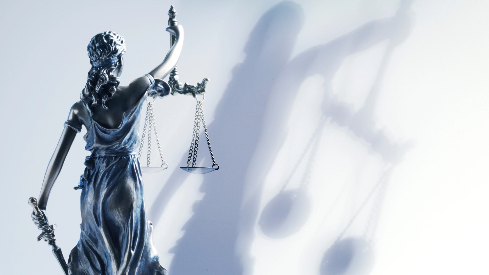 Eine silberne Statue von Justizia mit Schwert und Waage in der Hand