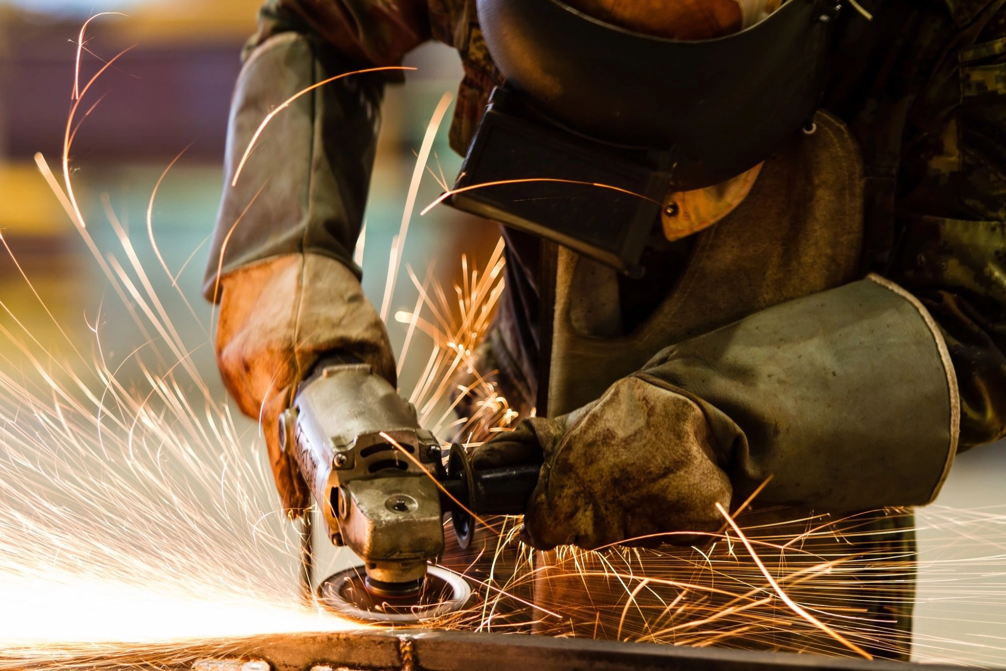 Ein Beschäftigter schleift Metall im Metallhandwerk