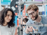 Zwei junge Ingenieure arbeiten an einem 3D-Drucker.